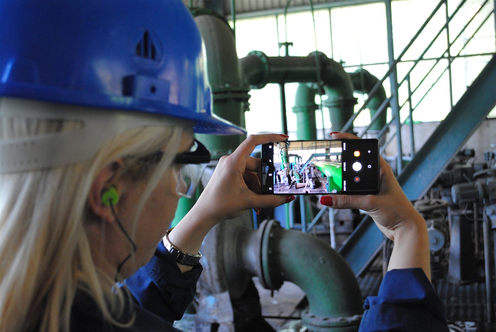 Field technician photographing industrial equipment with smartphone
